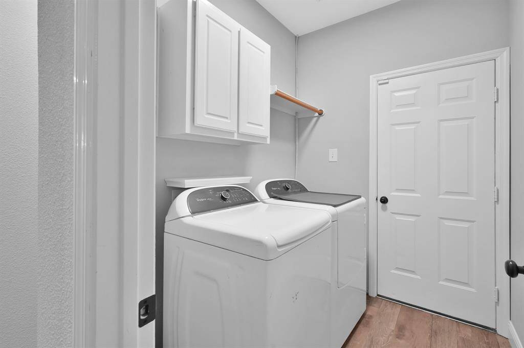 The laundry room offers extra storage cabinets, a convenient drying rack, and direct access to the attached 2-car garage.