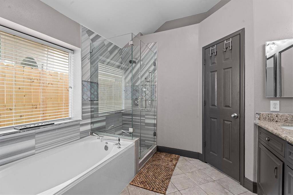 primary en suite bathroom with custom tile shower, soaking tub & double vanity