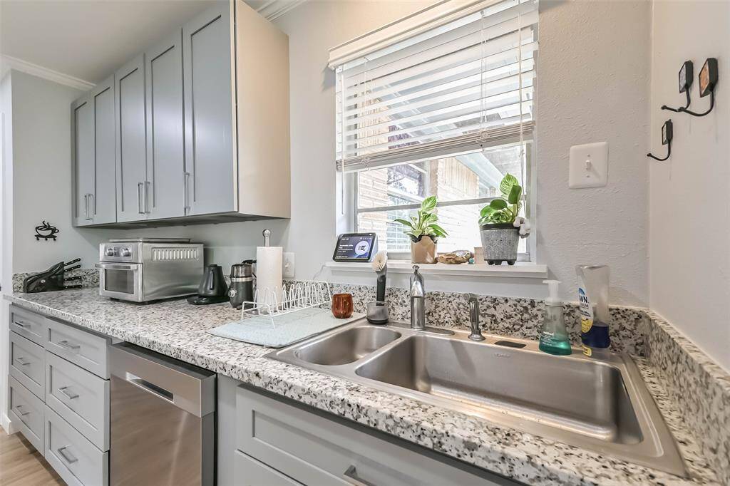 This dual bowl stainless-steel sink, with separate pull-out sprayer, sits in a window that overlooks the side patio and allows for natural light. Notice the stylish granite countertops
