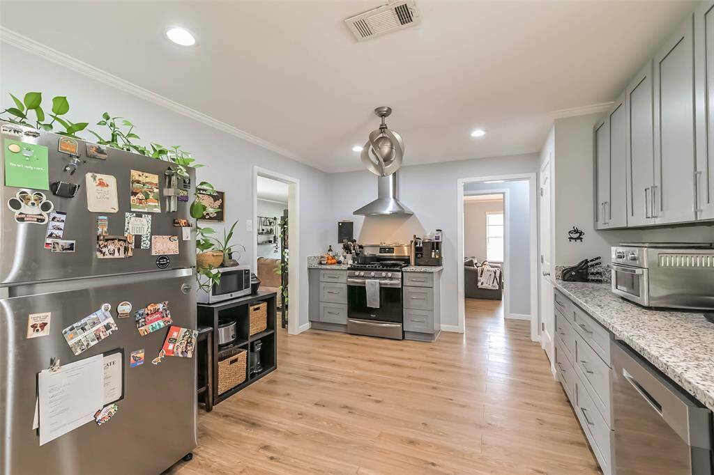 Last look across this gourmet kitchen which shows a modern fan, stainless steel appliances, decorative base & crown molding and cased doorways leading to dining room & the hall to bedrooms