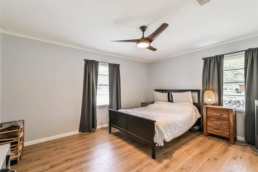 Nice-sized Primary Bedroom features vinyl plank floor, ceiling fan, pleasing paint color, decorative base & crown molding and 2 windows for natural light