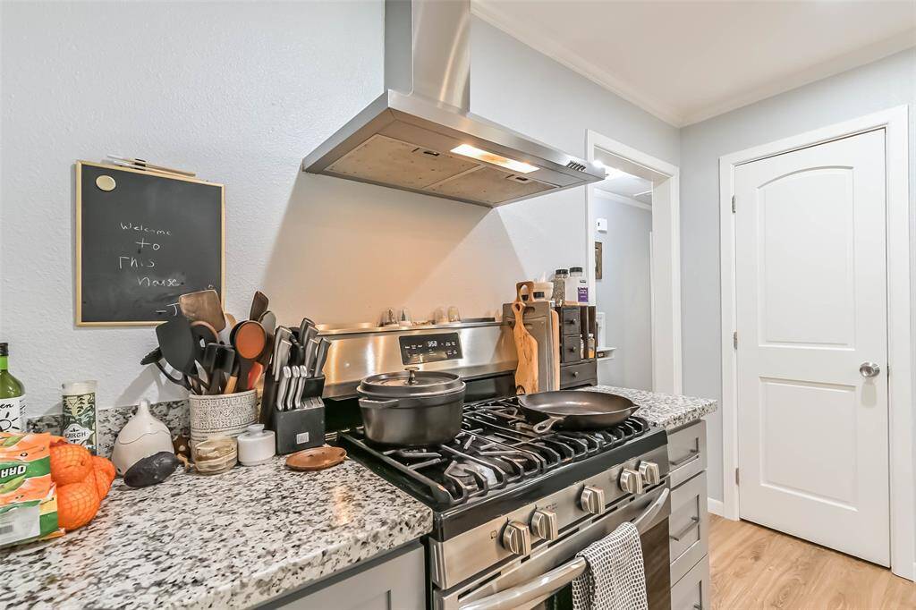 Look forward to cooking on this stainless-steel gas range with a contemporary vent hood. Behind the closed door is the pantry
