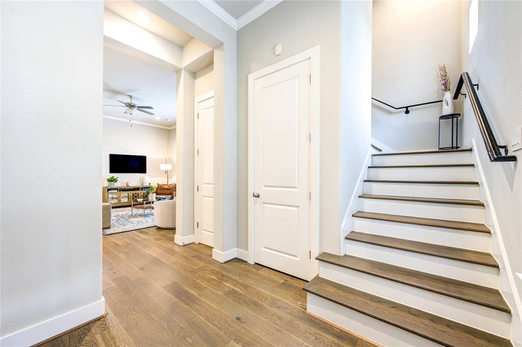 Elegant wood-tread staircase with matching French Oak flooring leads to the second level, seamlessly continuing the home’s refined aesthetic.