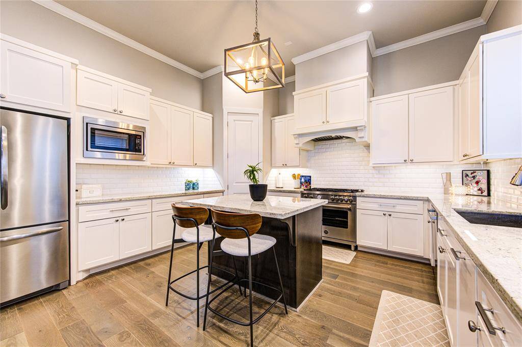 Chef-inspired kitchen with a large center island, subway tile backsplash, on-trend finishes, Bertazzoni 36” gas range, Bosch microwave and dishwasher, and custom cabinetry offering ample storage.