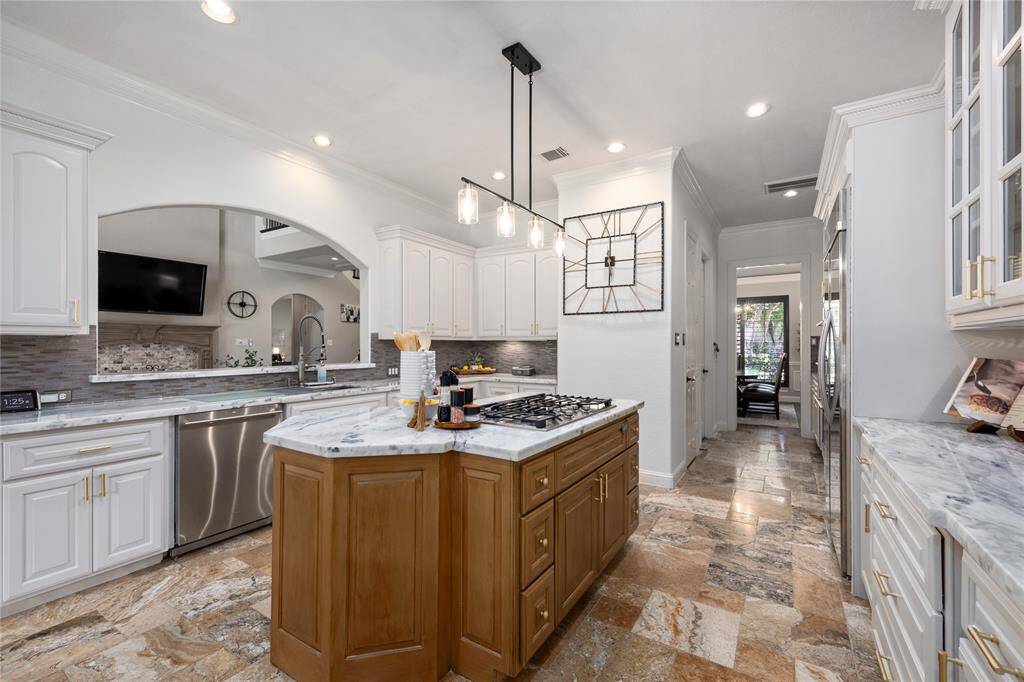 Wonderfully updated kitchen features updated cabinets, quartzite natural stone countertops, Gas Island Cooktop, updated lighting fixtures, and stainless steel appliances.