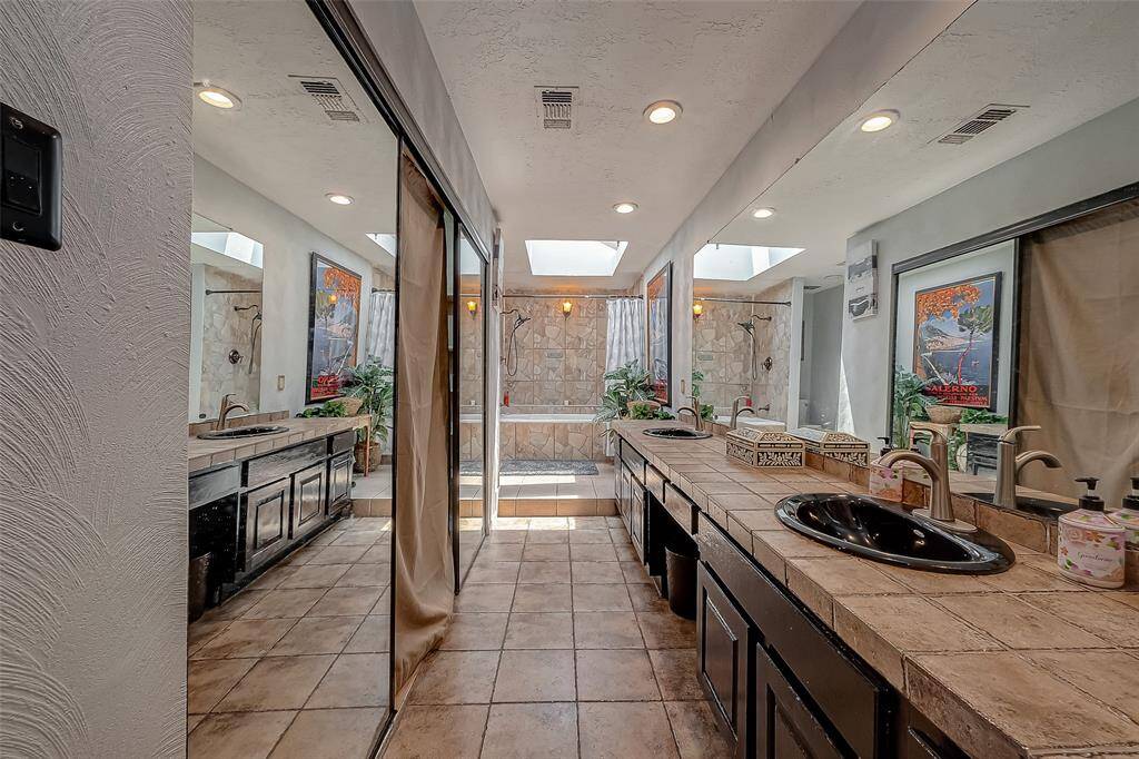 Primary bathroom with double vanities on a stone counter top.