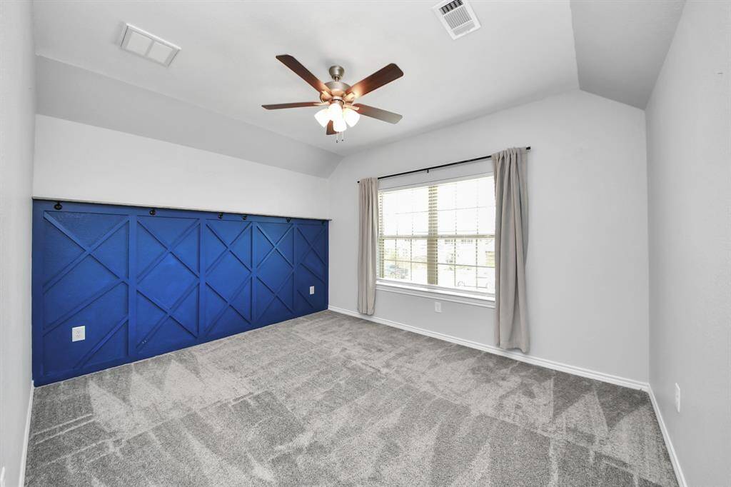 Spacious covered patio with a built-in fireplace, ceiling fan, and open view of the landscaped backyard.