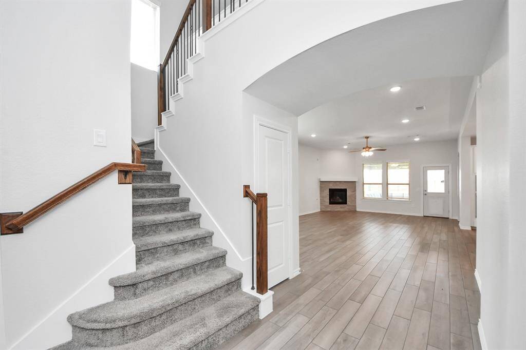 Open layout living space highlighted by a tile-accented fireplace and arched entryways.