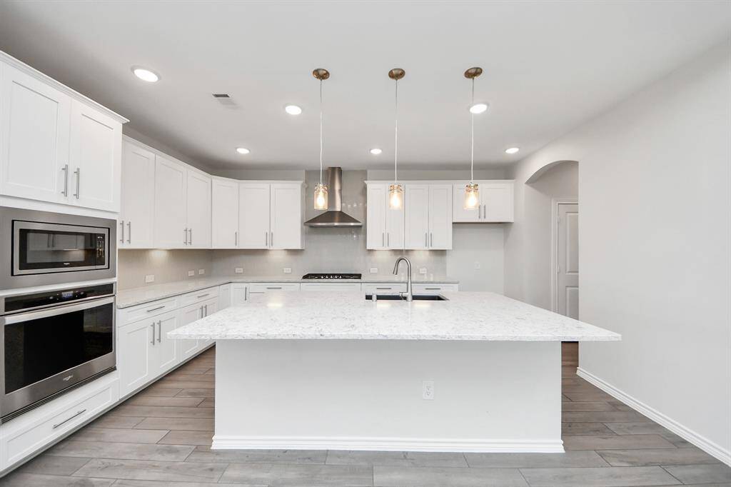 Bright primary suite featuring tray ceiling, large windows, and modern flooring throughout.