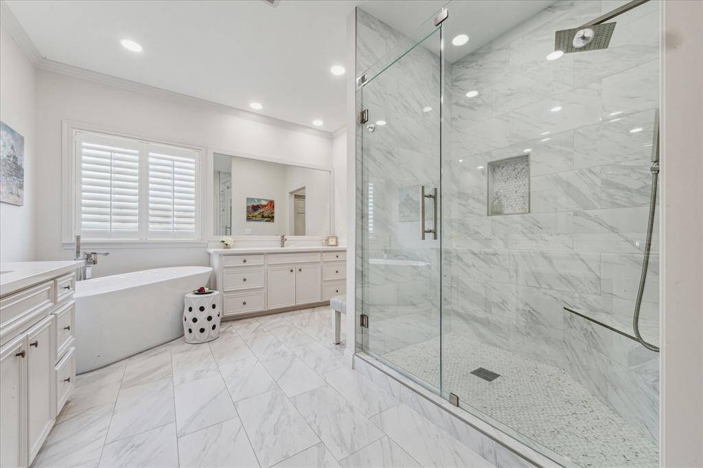 The spa-inspired primary bath includes a sleek glass-enclosed shower and a beautiful freestanding tub.