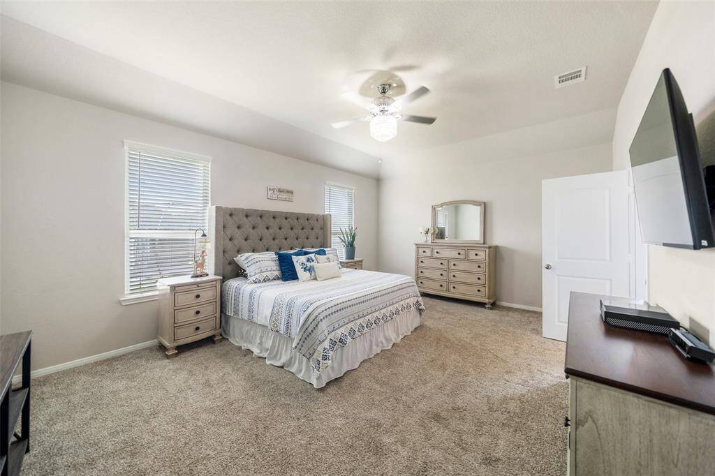 Spacious and bright primary bedroom featuring plush carpet, neutral walls, and a ceiling fan.