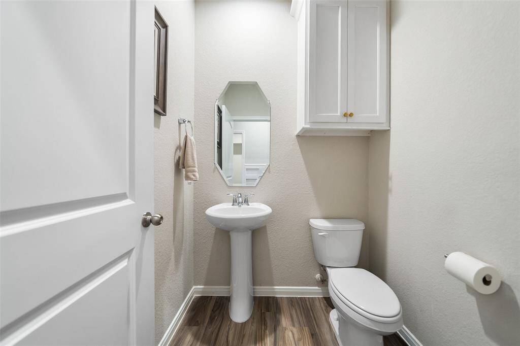 Convenient half-bathroom featuring a pedestal sink and wall-mounted cabinet.