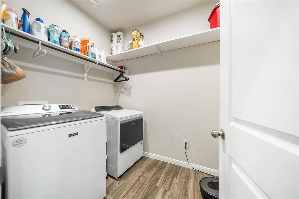 The spacious laundry room features ample shelving for storage of laundry supplies and a clean, neutral color scheme.