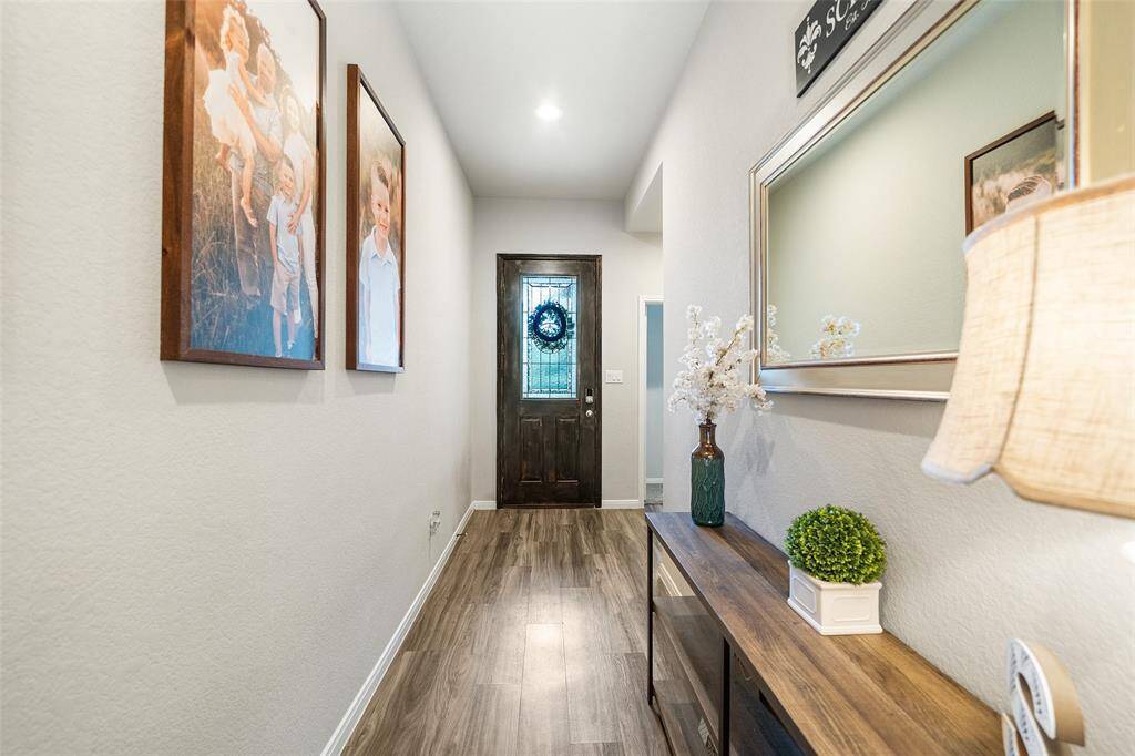 A welcoming hallway with LVP flooring leads to an 8ft decorative glass front door.