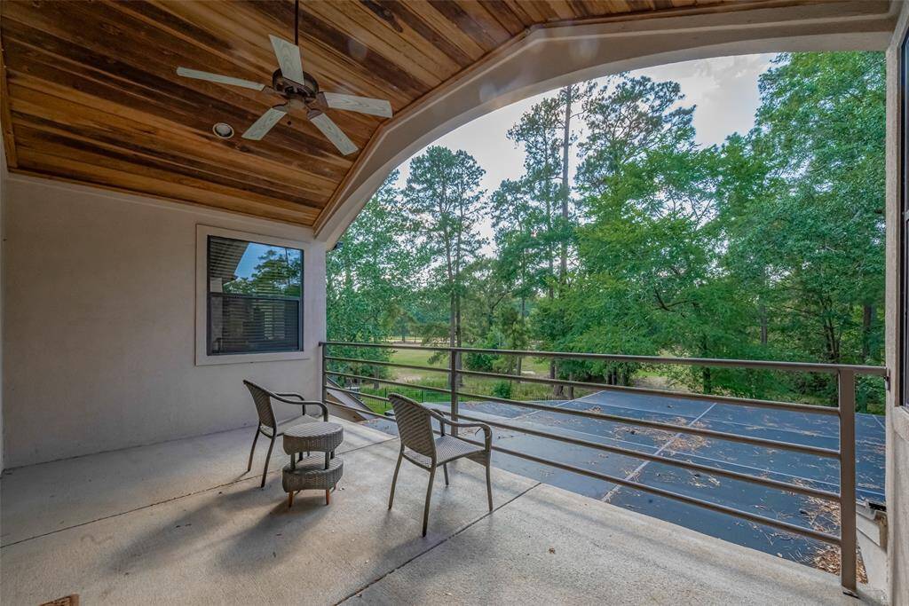 This covered balcony, located off the upstairs game room, features a richly stained cypresswood plank ceiling, recessed lighting, and a ceiling fan—all overlooking the 9th hole of Longwood Golf Club. The space is approximately 19' x 11', perfect for relaxing and taking in the view.