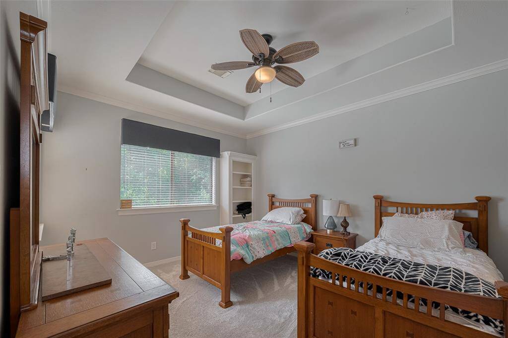 Upstairs Bedroom #3 features a tray ceiling, built-ins, crown molding, and a ceiling fan, all with views of the golf course. Approximately 16' x 13' in size, it also includes a spacious walk-in closet and a full ensuite bathroom.