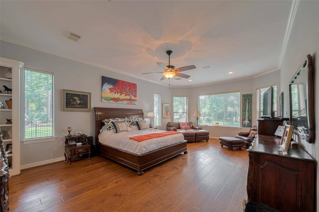 The impressive primary suite is located downstairs and showcases rich, hand-scraped red oak hardwood floors throughout. Large windows flood the space with natural light, highlighting the deep, stained tones beautifully.
