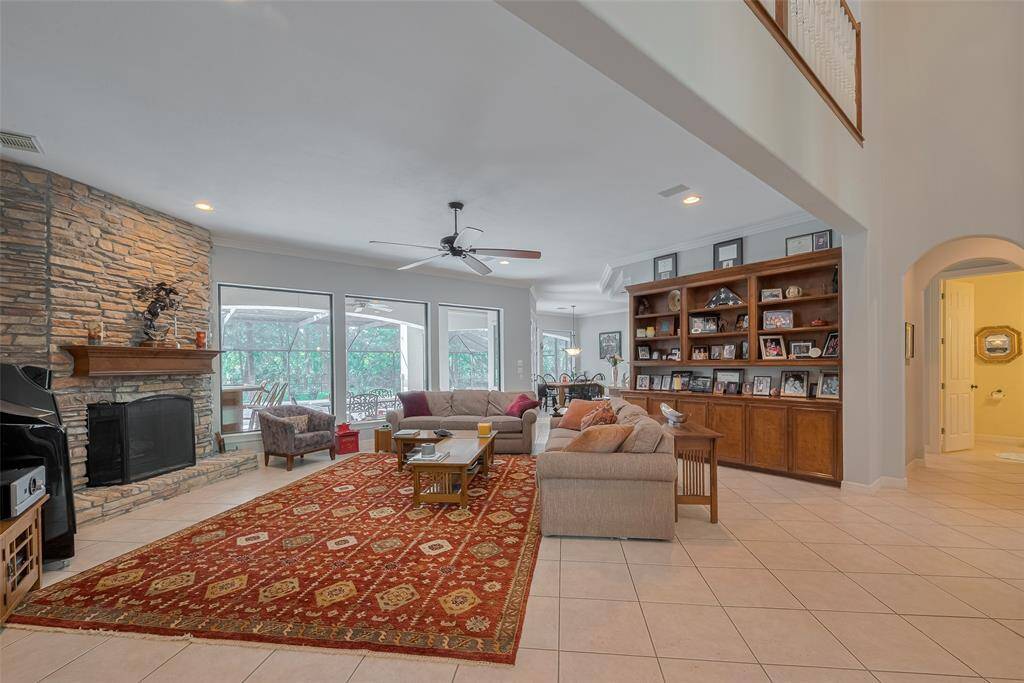 This custom home features soaring ceilings throughout, including 10-foot ceilings in the open-concept den. A wall of windows provides stunning views of the pool and golf course, filling the space with natural light. Highlights include custom built-ins, a stacked stone fireplace, and built-in surround sound wiring for an elevated living experience.