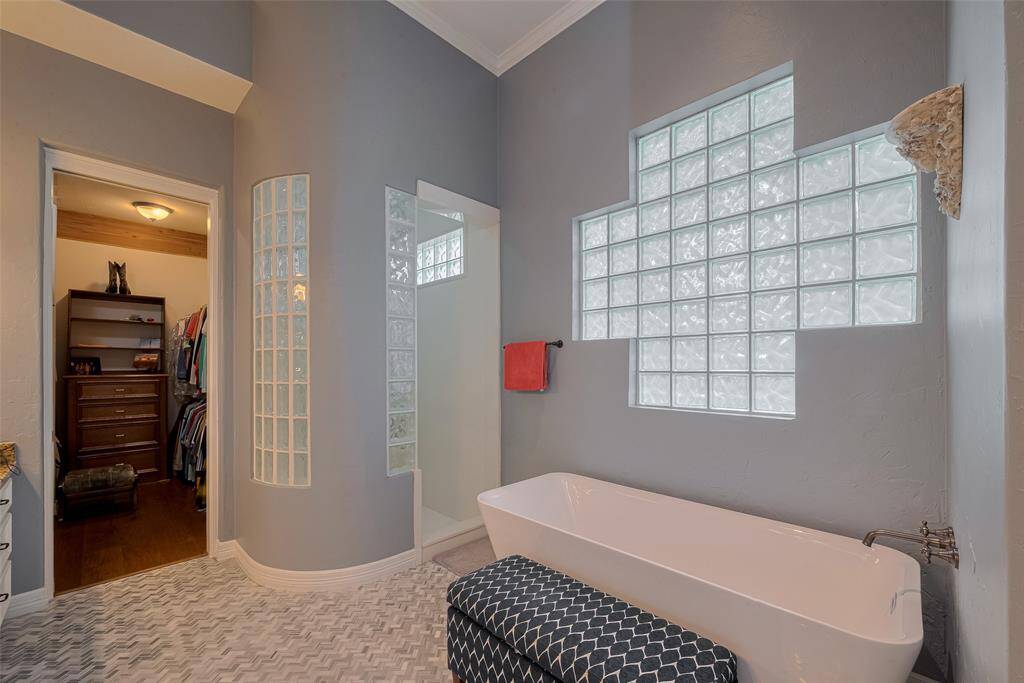 The floors are truly stunning, featuring herringbone marble tile beneath the freestanding soaker tub. The bathroom also includes a spacious walk-in shower.