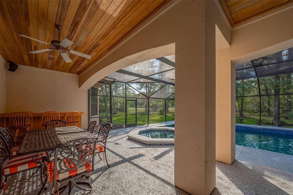 A spacious covered patio extends from the den and kitchen, showcasing more of the rich cypress wood planks on the ceiling.