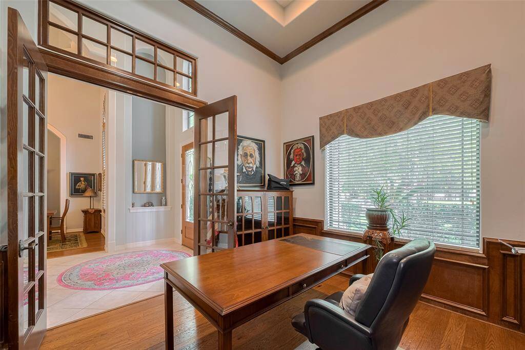 You might actually enjoy working in this stunning private study, featuring double 8-foot glass French doors, a transom window, and an impressive tray ceiling soaring to approximately 14 feet.