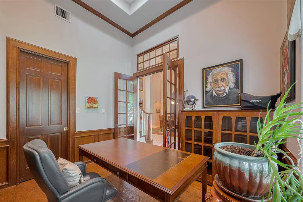 Elegant stained wainscoting and a custom built-in desk/bookcase (not pictured) complement the rich Amish hand-scraped red oak floors, installed around 2022. Tucked behind the door, you'll find a spacious walk-in closet.