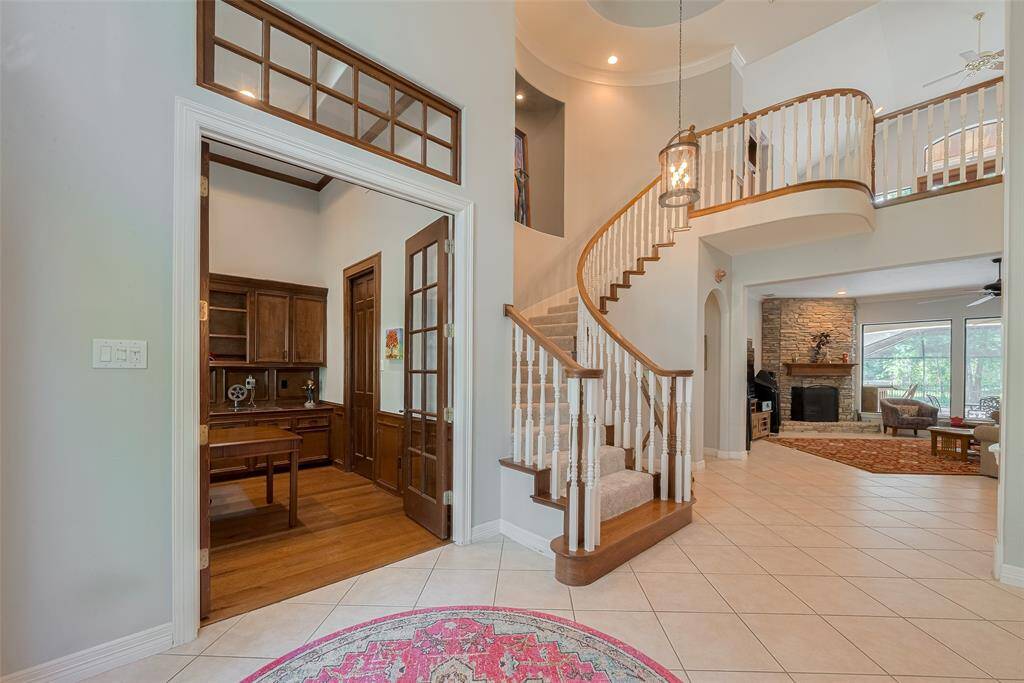 As you enter the foyer through double leaded-glass French doors, your eyes are immediately drawn upward to the soaring 20-foot ceilings. To the left, you'll find a private study, while just ahead, a custom, elegant staircase leads to the upper level.