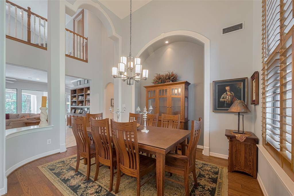 The formal dining room showcases dramatic 20-foot coffered ceilings, graceful arches, detailed trim work, and stained plantation shutters. Rich Amish hand-scraped red oak hardwood floors add warmth and elegance to the space.