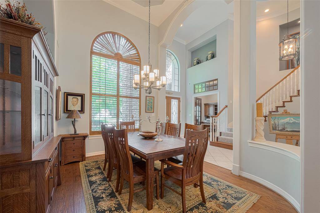 Here's another view of the formal dining room, seamlessly open to the home's foyer and grand staircase. Towering windows echo the soaring ceilings, offering picturesque views of the mature trees and beautifully landscaped surroundings.