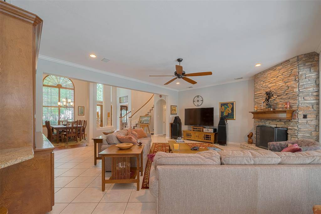 The den is spacious and flows effortlessly into the dining room, foyer, and large island kitchen. It features a stone fireplace with gas connections and gas logs, built-in surround sound speakers, and an updated ceiling fan.