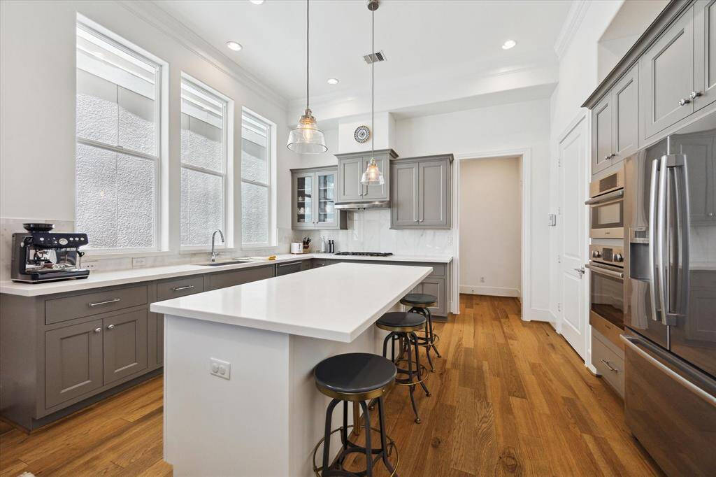 The bright, open dining area connects to a modern kitchen. It features wood flooring and elegant cabinetry while ample natural light streams through multiple windows.