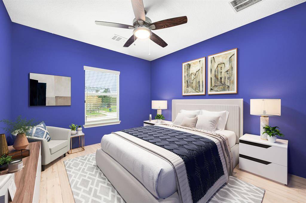 Secondary bedroom features warm vinyl plank, custom paint, dark stained ceiling fan with lighting and a large window with privacy blinds.