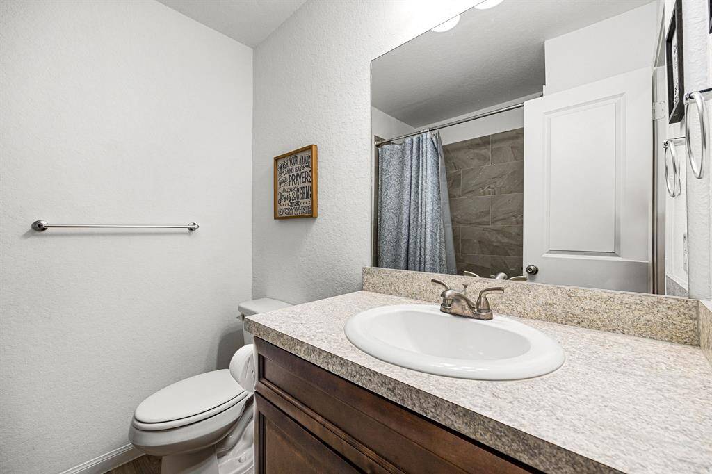 Secondary bathroom features light countertops and dark cabinets, neutral paint, shower/tub combo with tile surround, large mirror, tile floors, sleek fixtures and modern finishes, plenty of space to accommodate any visiting family or guests.