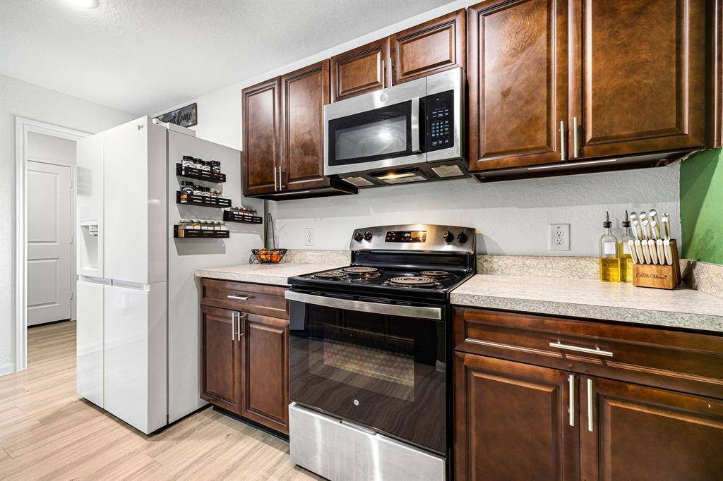 This stunning kitchen displays such a beautiful contrast with the dark stained cabinets, neutral paint, SS appliances, breakfast bar, recessed lighting, and high ceilings.