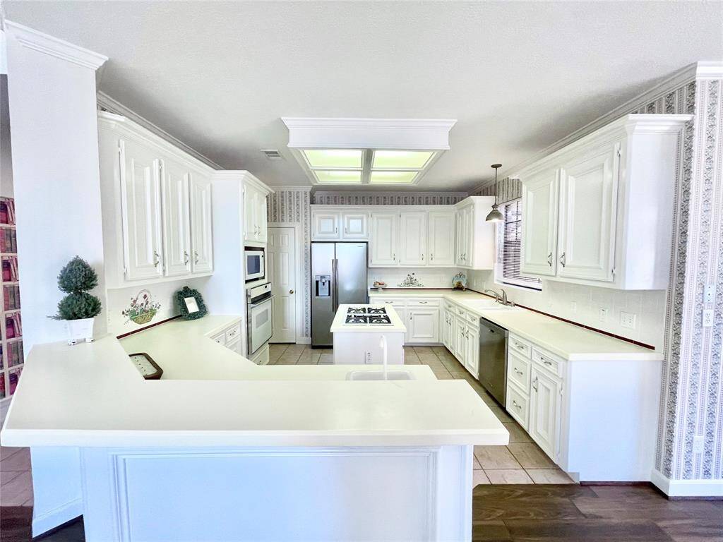 Bright white kitchen with lots of cabinets, counter space, island w/ gas cooktop, second sink, breakfast bar that opens up to the living room, & refrigerator included.