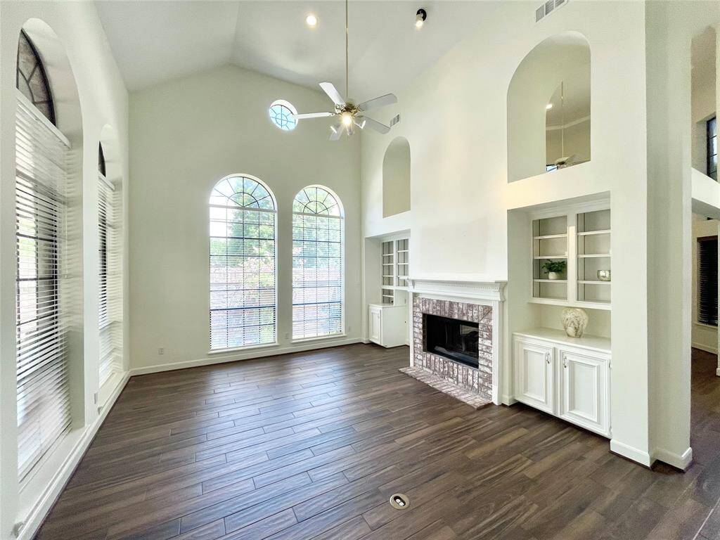 One can appreciate the arches and all the natural light this oversized living room has to offer. Built-in cabinets and bookshelves make a great addition and the floating fireplace is a must have for the winters. Walls of arched windows really give this room charm.