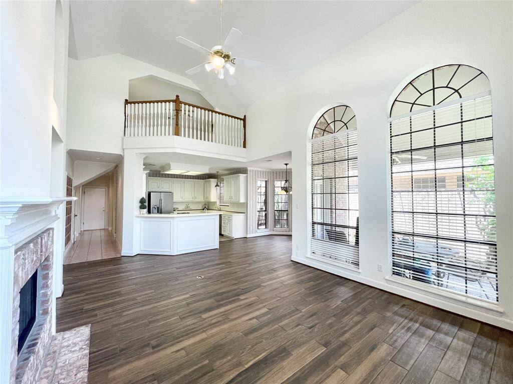 Open concept living area with new porcelain tile, two story ceilings,  full views of the kitchen, covered patio, and game room upstairs.