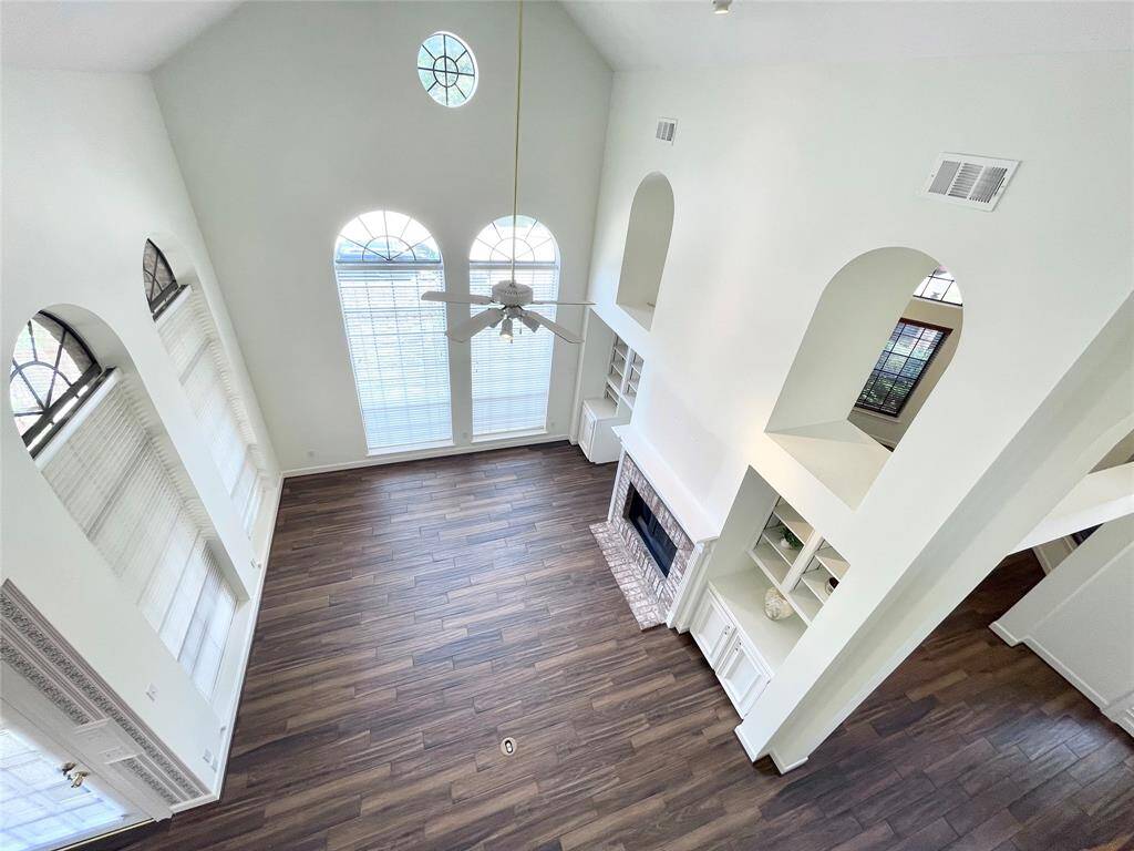Views of the living area from the balcony of the second floor game room. Soaring 2-story ceilings, open arched niches, porcelain tile, plenty of natural light, oversized arched windows, floating wood burning fireplace, built-in cabinets and shelving.