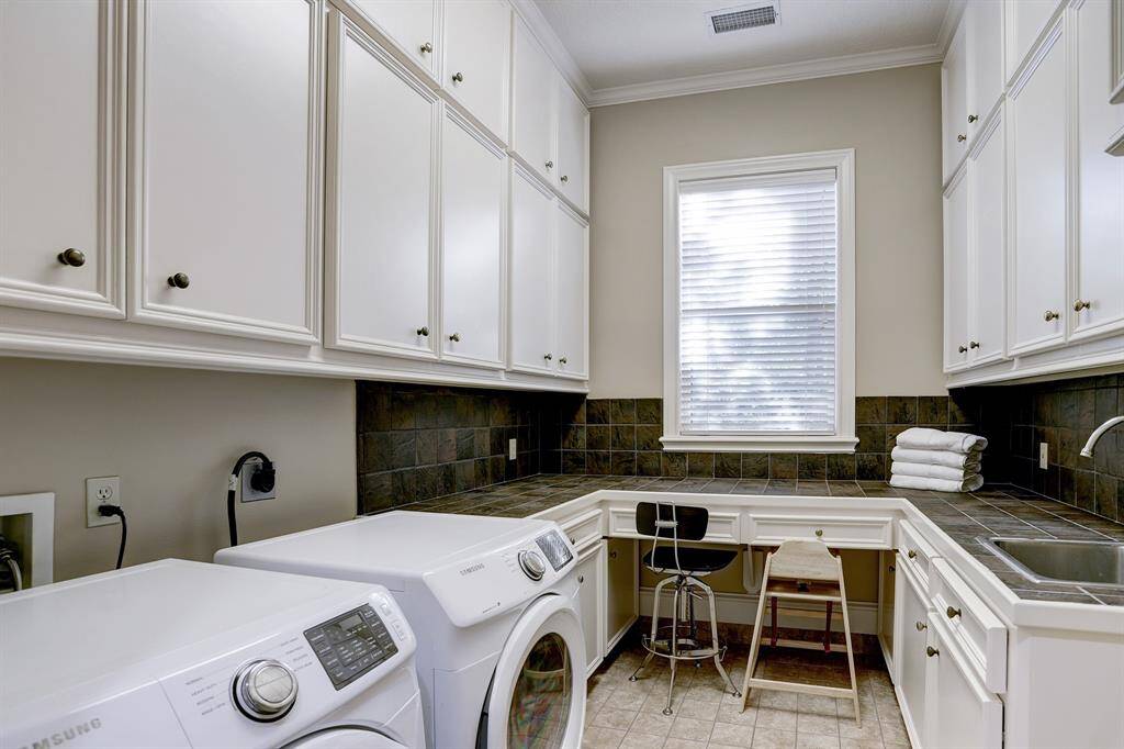 Fantastic utility room offers its own sink, tile floors, custom cabinets, tile counter tops, and even a desk area! There is more than enough space for storage, folding laundry, sewing, etc.