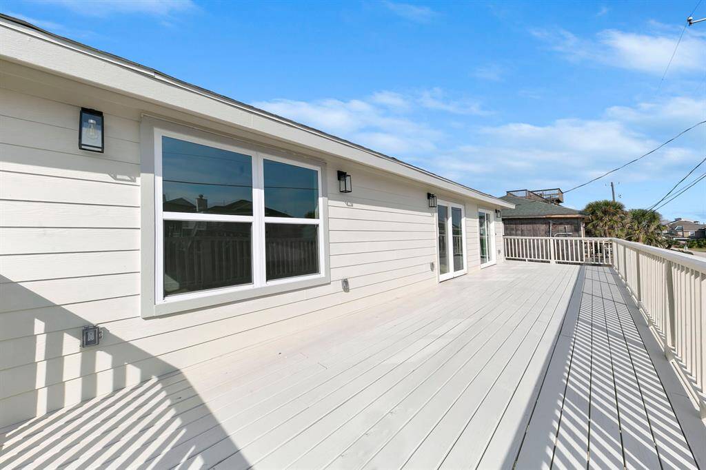 This home features a spacious, sunlit deck with modern siding, large windows, and French doors, perfect for outdoor relaxation and entertaining.