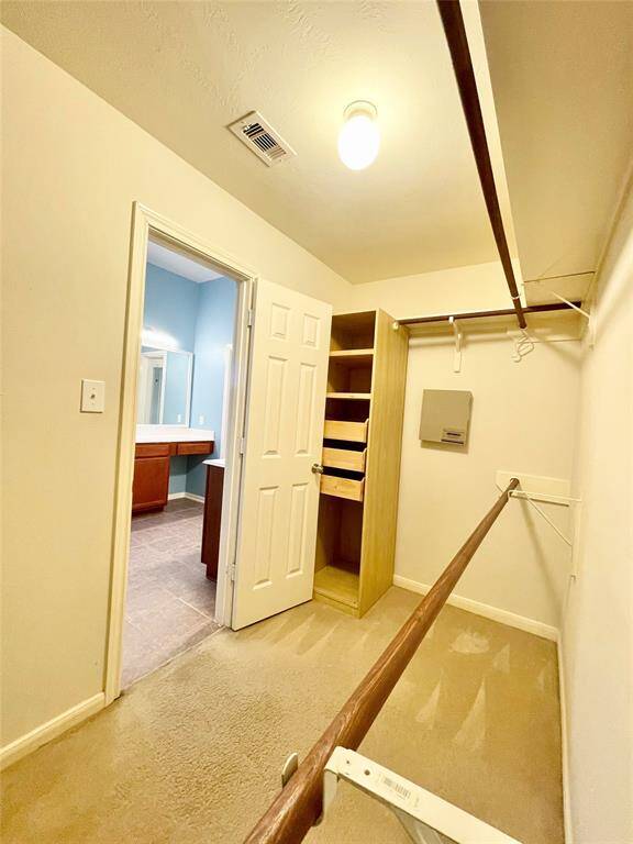 Spacious master walk-in closet with built-in shelves and hanging rods. The area is well-lit, offering a functional and organized space.