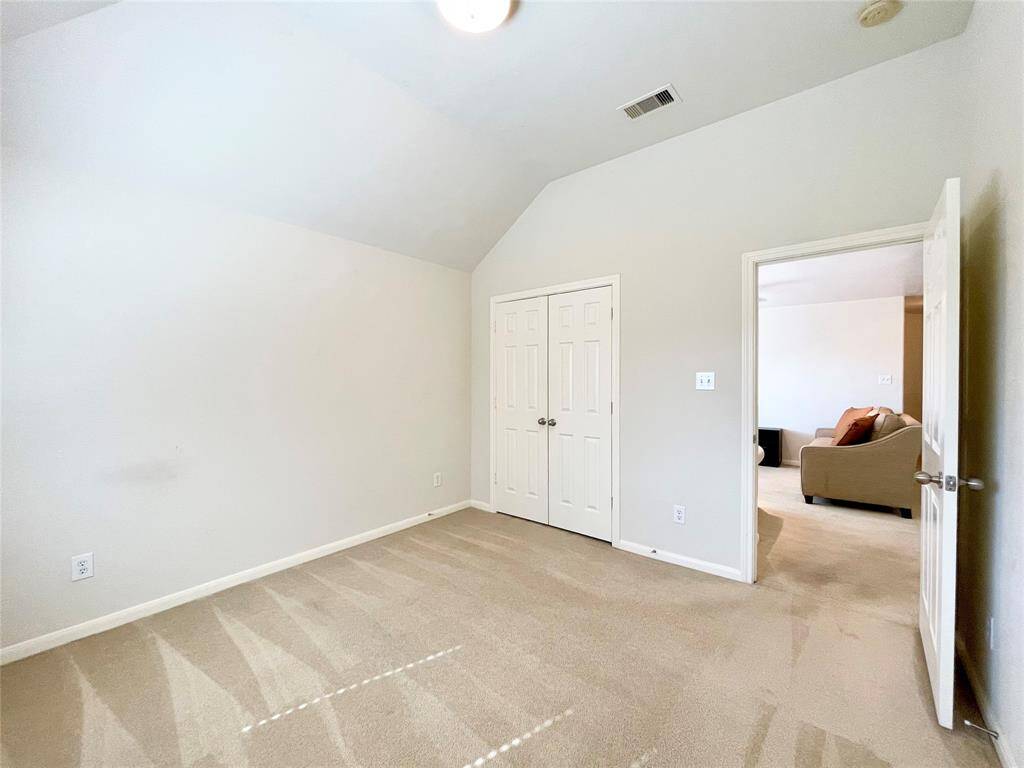 Bedroom # 2 carpeted room with neutral walls and a vaulted ceiling. It features a double-door closet.
