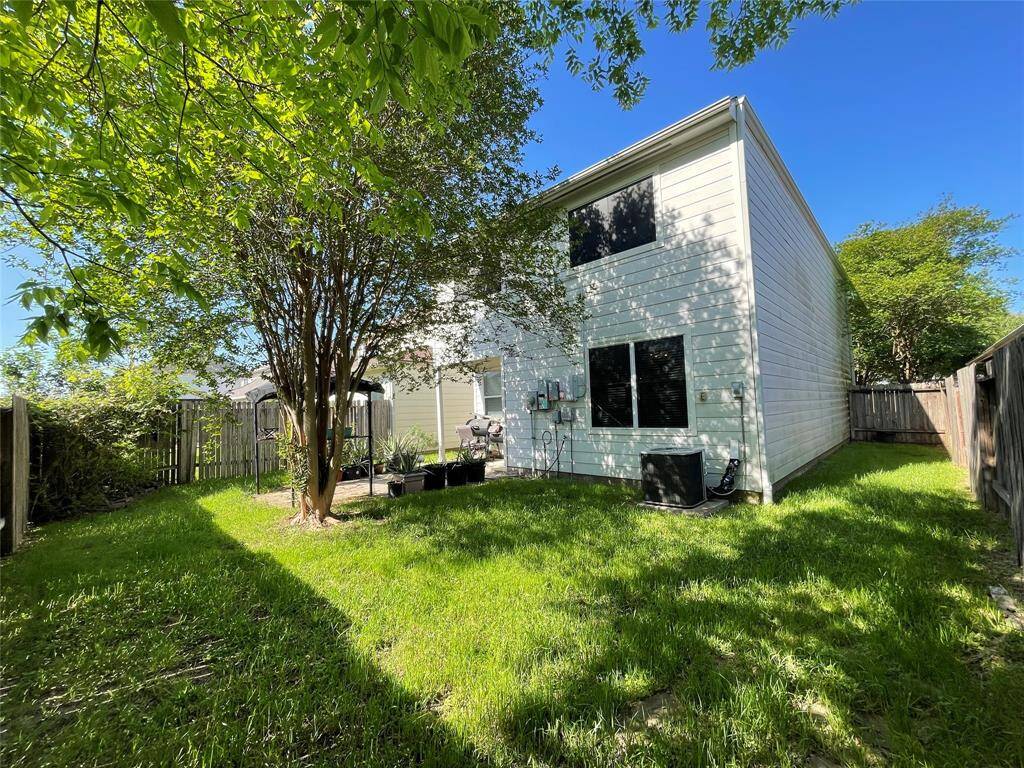 Charming backyard with lush greenery, a mature tree, and a well-maintained lawn.