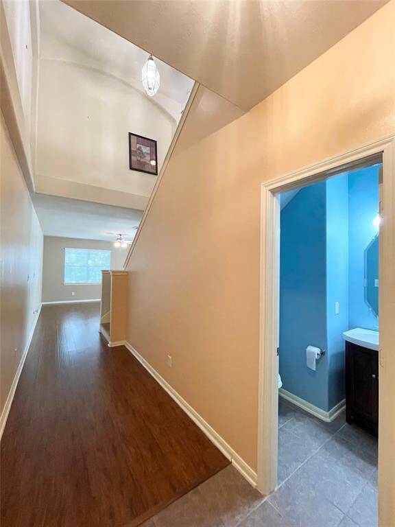 Welcoming hallway with high ceilings, wood flooring, and a bright, blue-painted bathroom to the right.
