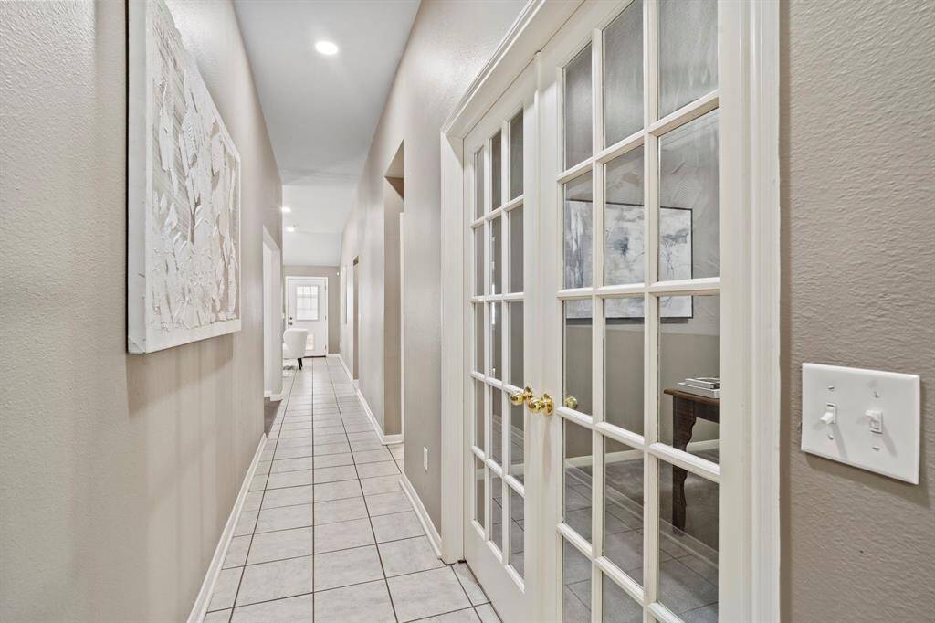 A long, tile-lined hallway connects the entry to the main living areas and bedrooms, also with a private study tucked behind elegant French doors.