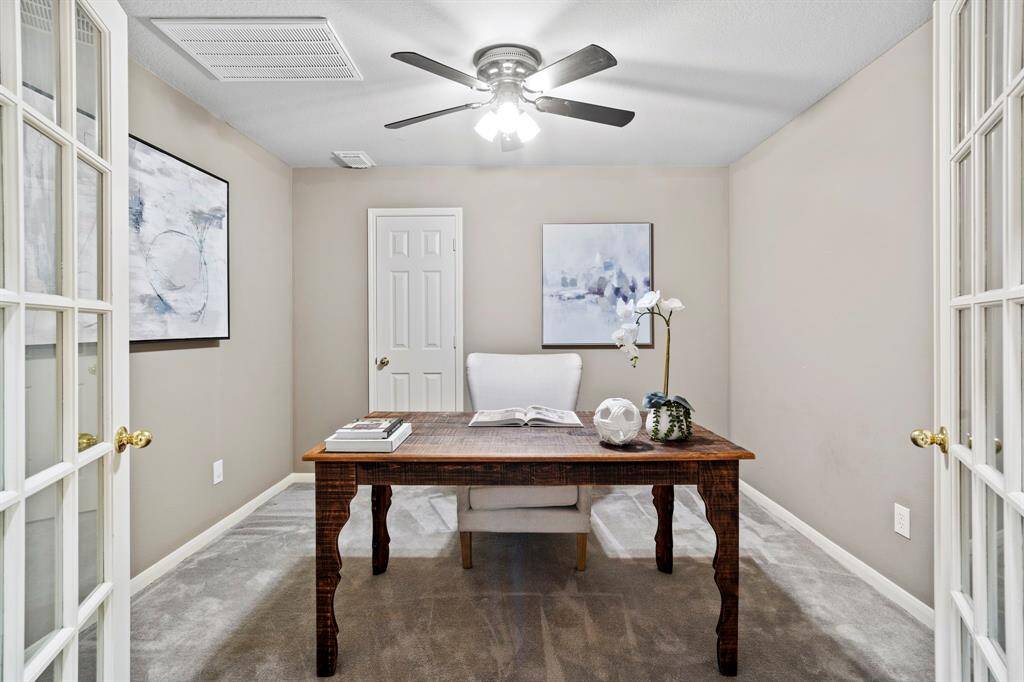 The dedicated home office offers a quiet space to focus, with soft carpet underfoot, neutral paint, and a ceiling fan for year-round comfort.