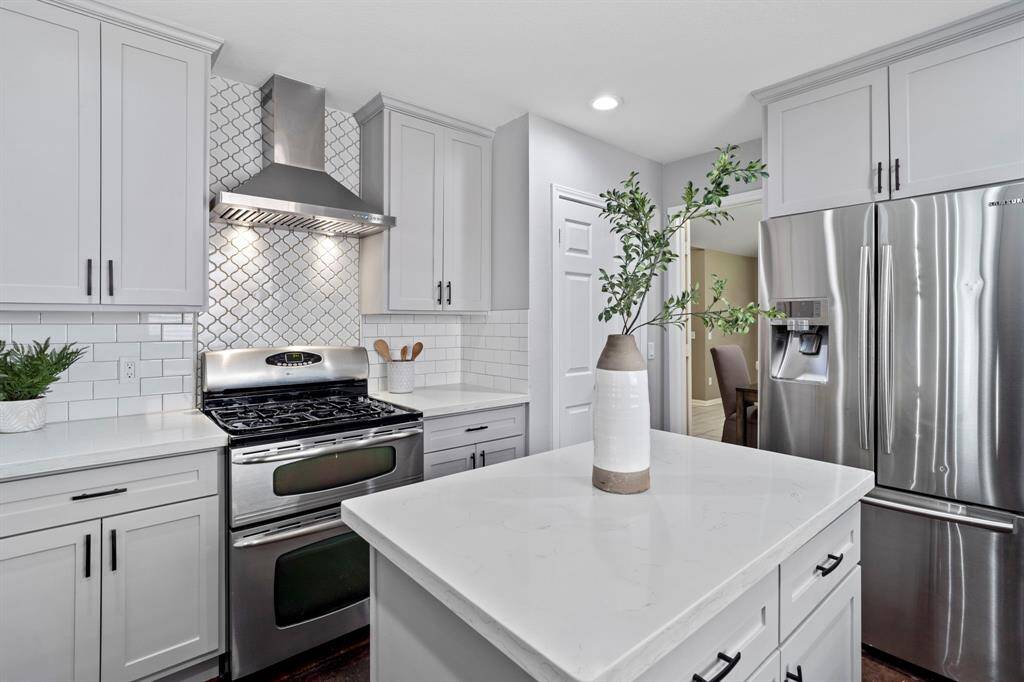 A custom backsplash and vent hood create a striking focal point above the gas range, combining beauty with performance.