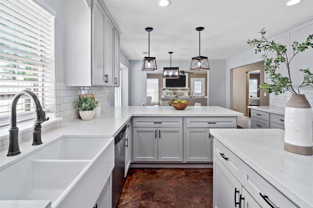 A deep farmhouse sink beneath a wide window adds charm and convenience, while abundant cabinetry ensures easy storage.