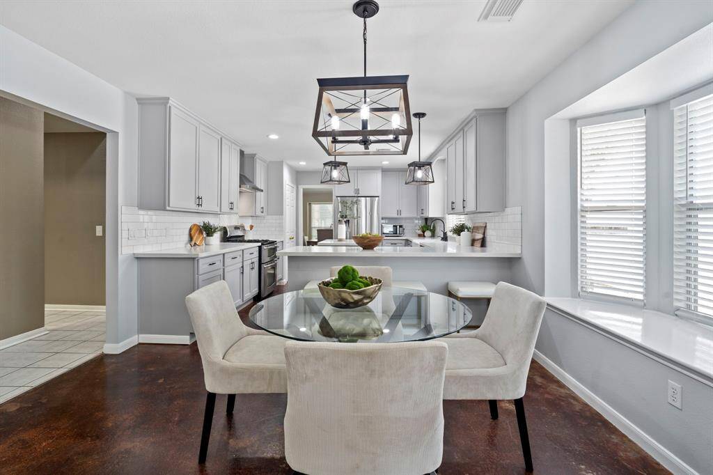 Enjoy casual meals in this cozy dining space, where a stylish light fixture hangs above and natural light pours in from multiple windows.
