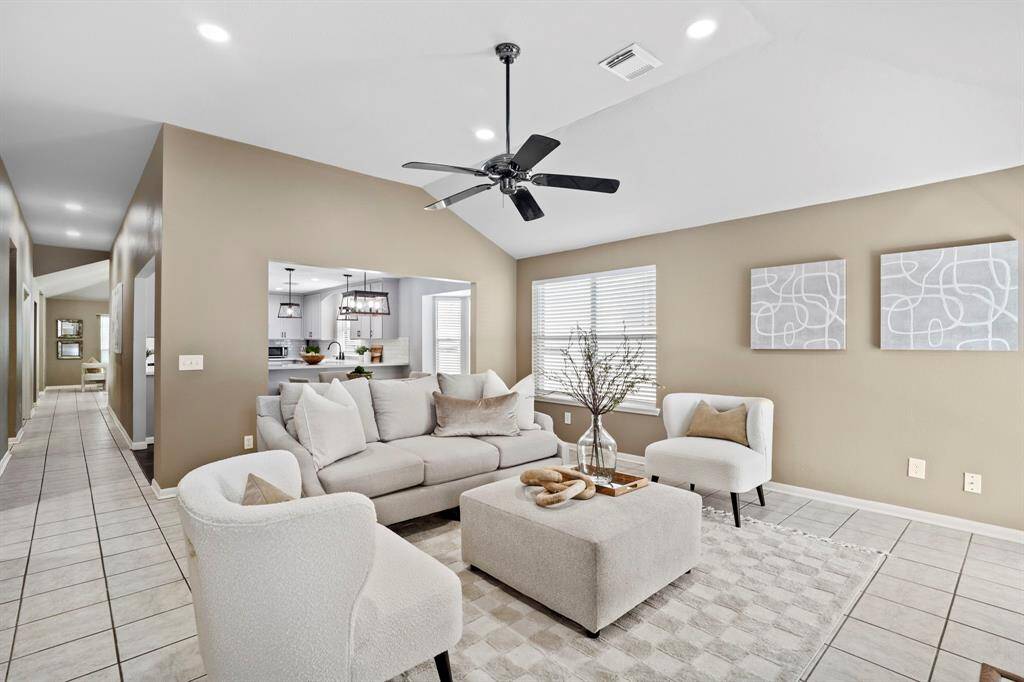 This inviting family room offers an airy layout with vaulted ceilings, neutral tones, and abundant natural light, perfect for gathering or relaxing at home.
